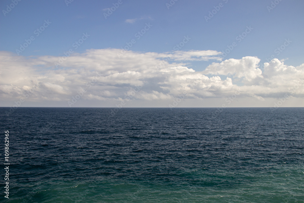 The dark sea water and sky with clouds, visible horizon