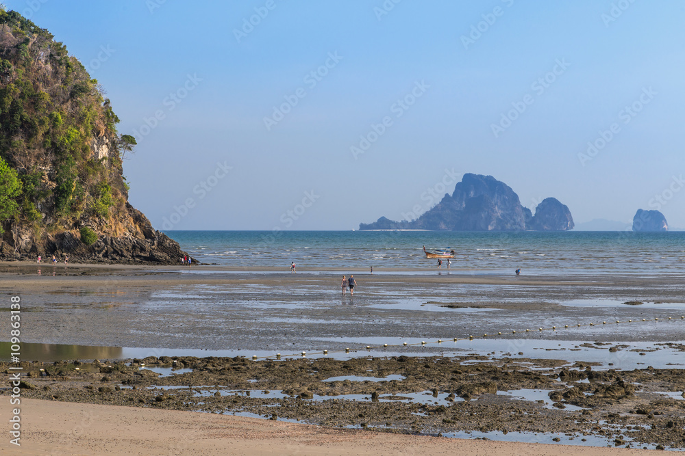 Tourists walking in shallow water during low tide at aonang beach, Krabi, Thailand