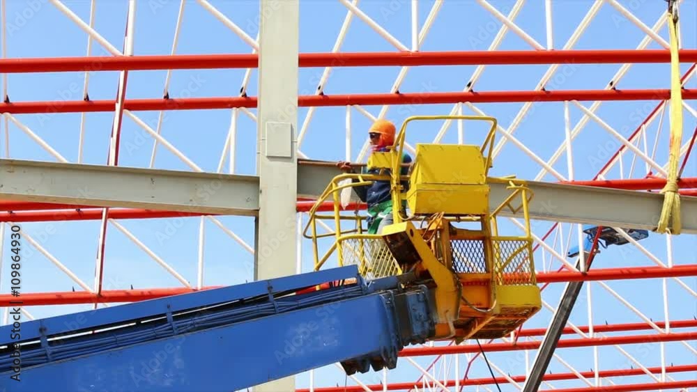 construction worker working at construction site using lifting boom machinery construction worker working at construction site using lifting boom machinery