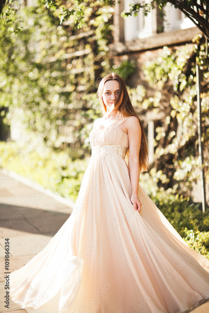 Attractive young woman with long dress enjoying her time outside in park sunset background