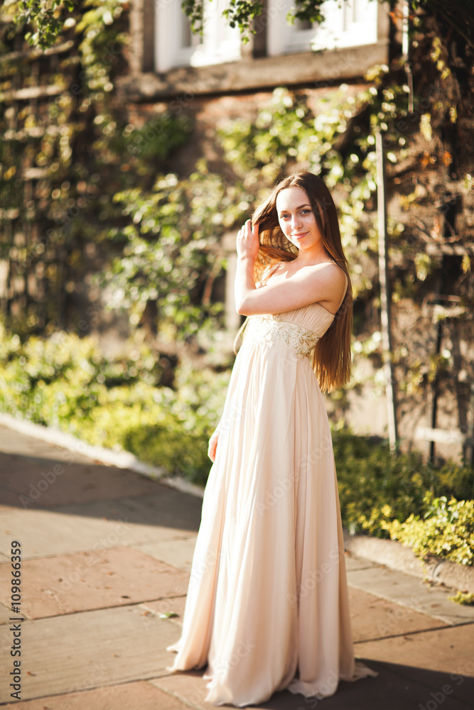 Attractive young woman with long dress enjoying her time outside in park sunset background