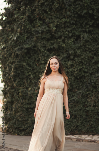 Beautiful girl, model near the wall of leaves and bushes in park