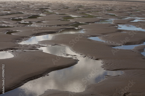 Rhossili Beach. Rossili beach has extreme tides. At low tide a large beach is left exposed showing up the uneven surface of the normally underwater sand leaving small waterholes across the beach. photo