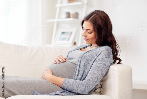 happy pregnant woman lying on sofa at home
