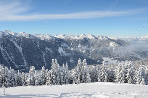 Beautiful view of the snow-covered spruces, mountains and low clouds in winter