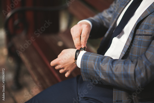 Confident businessman looking on his wrist watch in suit