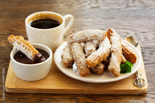 Churros with hot chocolate and powdered sugar.
