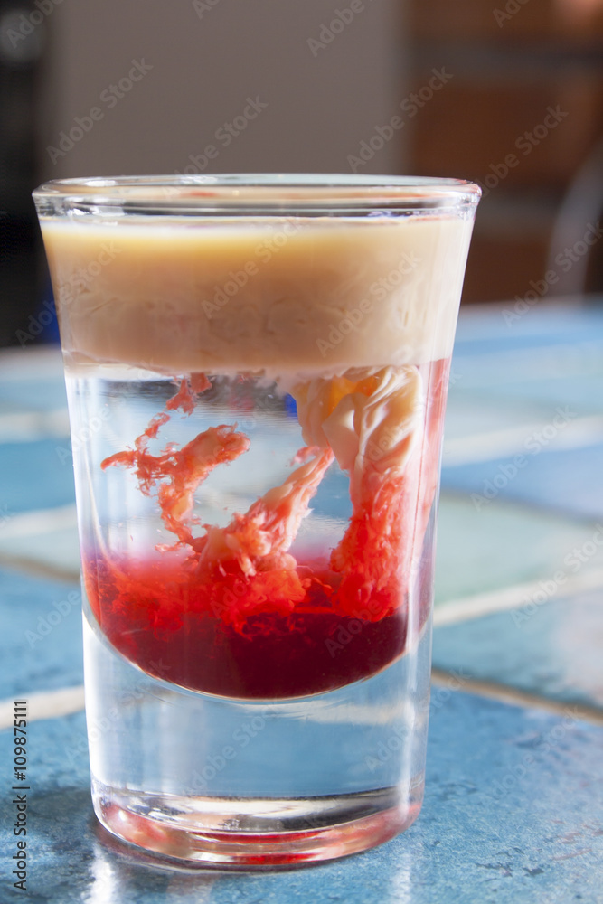 Monkey-brain cocktail in a shot glass on blue tiled bar - table. Stock  Photo | Adobe Stock