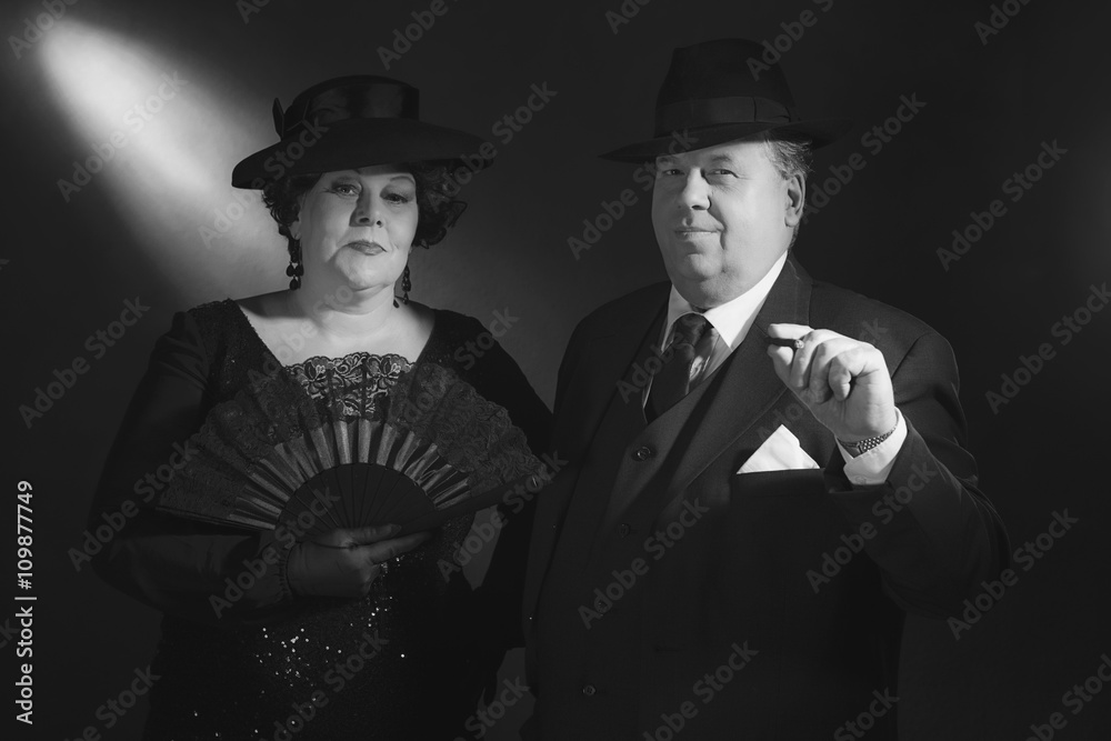 Vintage well dressed 1940s couple with fan and cigar. Black and