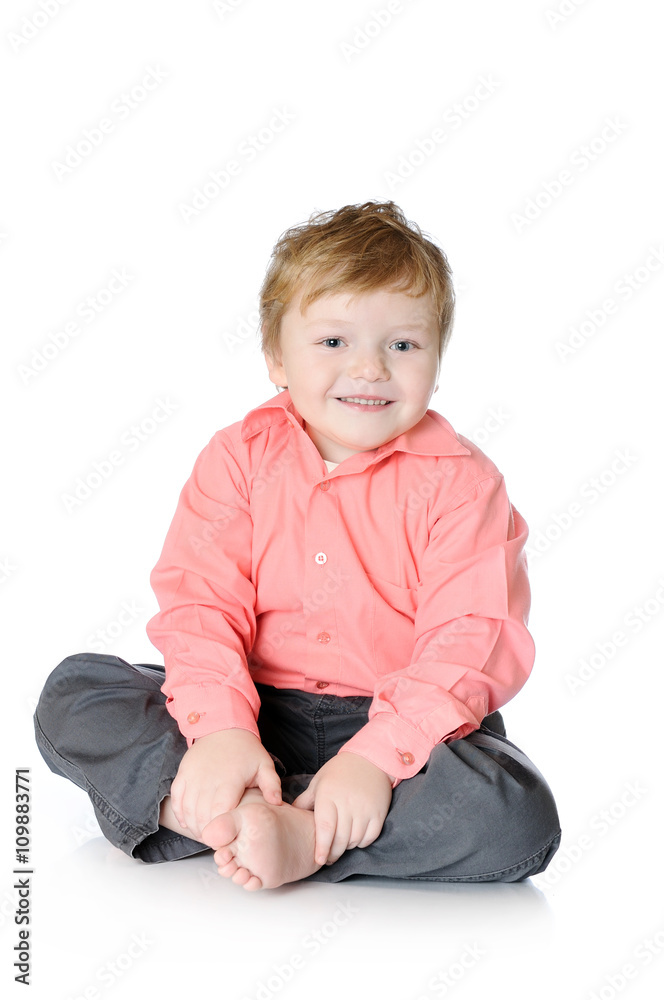 Adorable little boy smiling, sitting on the floor, studio shot, isolated on white background Adorable little boy smiling, sitting on the floor, studio shot, isolated on white background