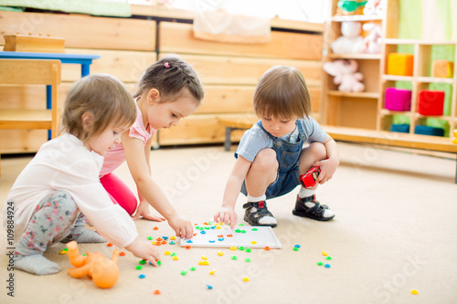 kids playing mosaic game in kindergarten room 