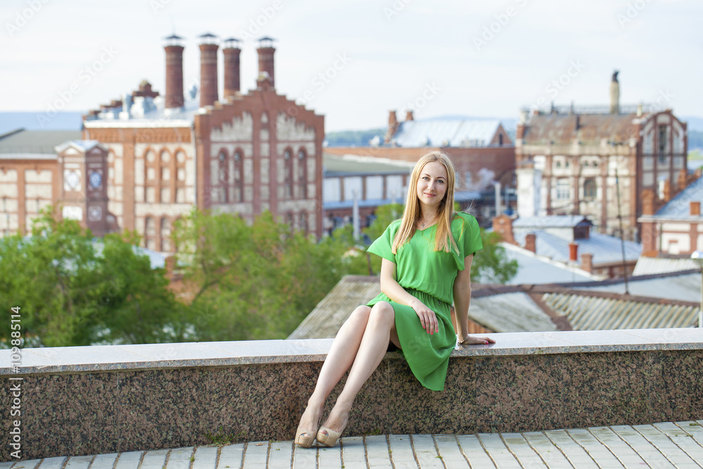 Young beautiful woman in green dress posing outdoors in sunny we