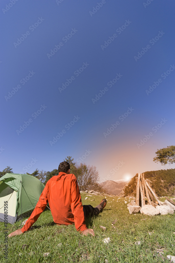 Man camping with a tent in the mountains in the summer on a sunny day.