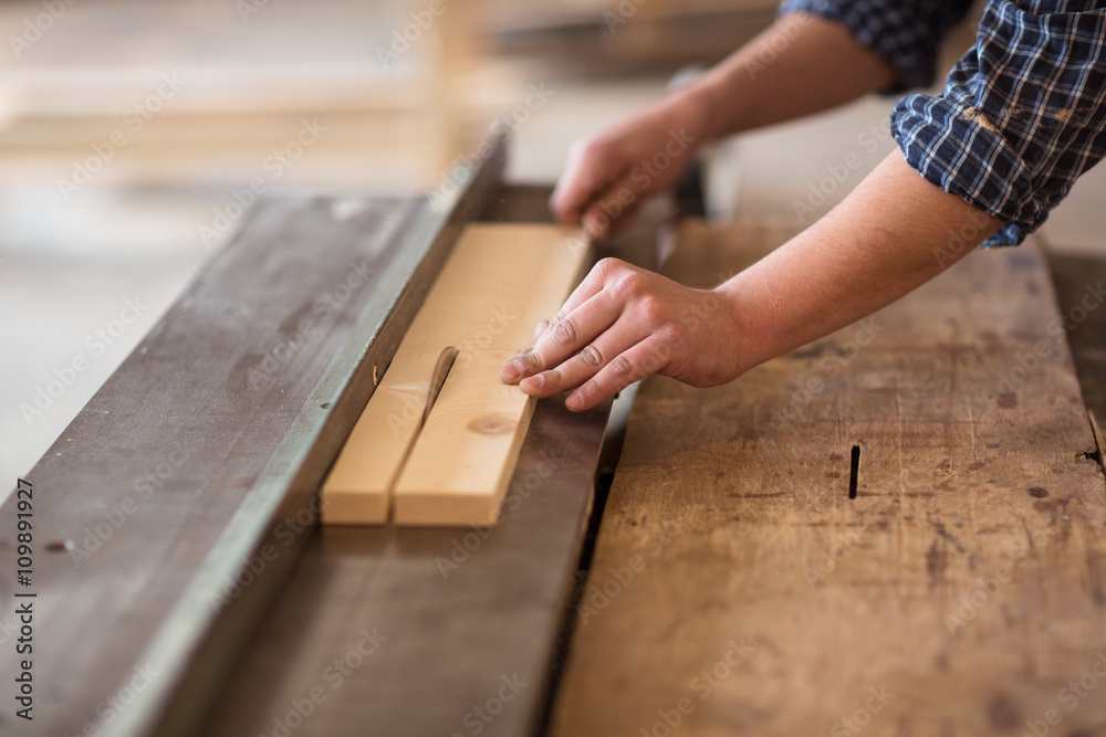 Skilled carpenter working in his woodwork workshop, using a circ Skilled carpenter working in his woodwork workshop, using a circ