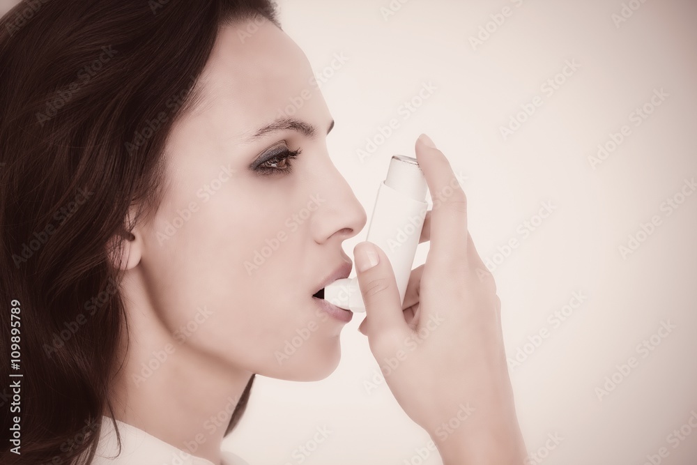Composite image of asthmatic brunette using her inhaler Composite image of asthmatic brunette using her inhaler