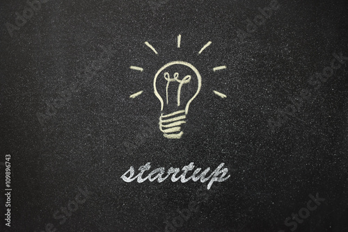 light bulb painted on a board and the text "startup"