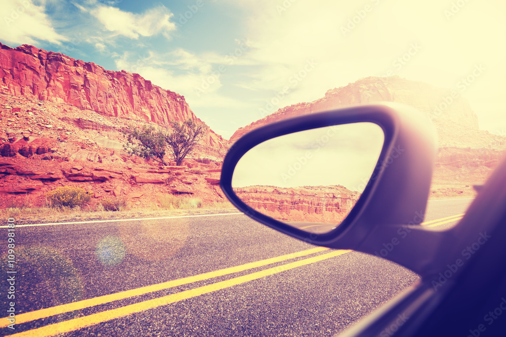 Vintage stylized car wing mirror with lens flare effect, focus on mountains, travel concept.