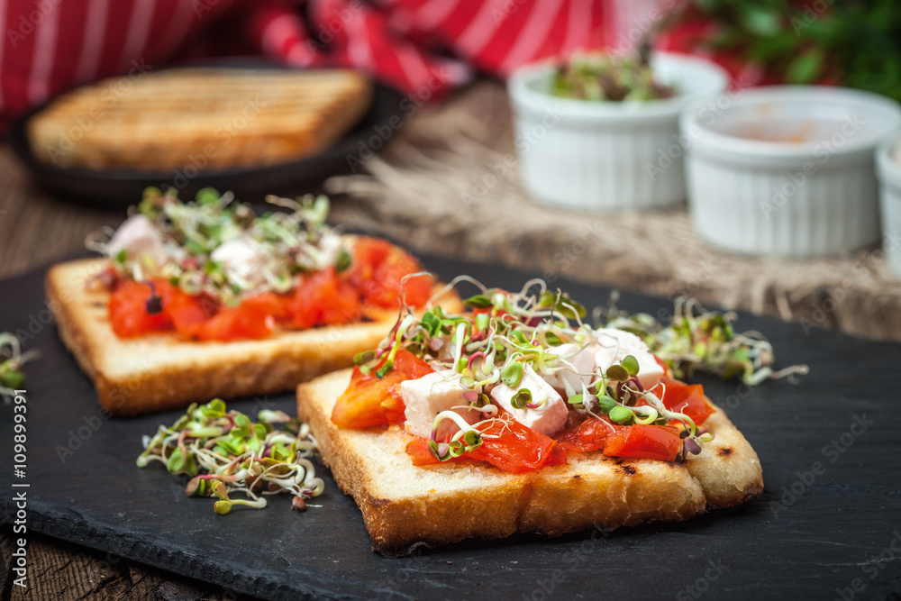Grilled toasted bread with roasted tomatoes, feta cheese and radish sprouts. Grilled toasted bread with roasted tomatoes, feta cheese and radish sprouts.