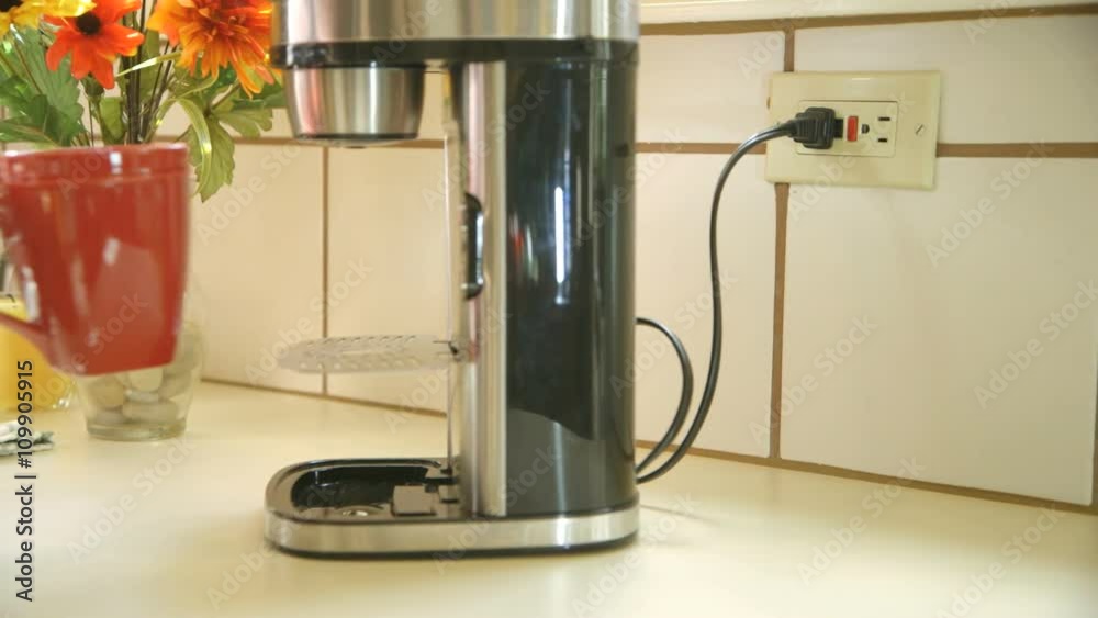 An environmentally minded woman conserves energy by unplugging the coffee maker after the coffee is ready.