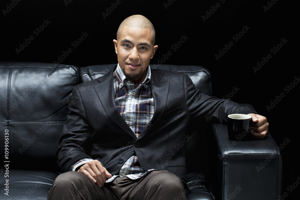 smiling young mafia boss having a cup of coffee. Stock Photo | Adobe Stock