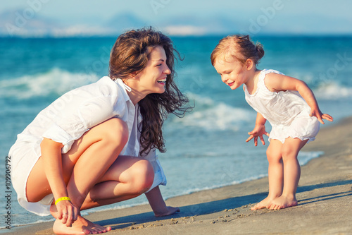 Mother and little daughter playing on the beach