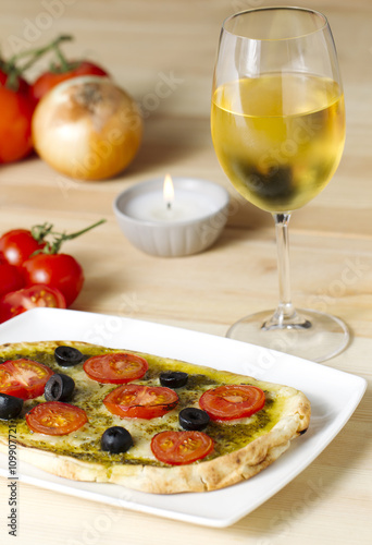 pesto pizza with tomatoes and black olives