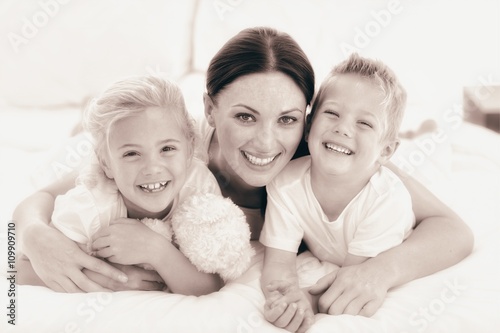Happy mother and her children lying on a bed