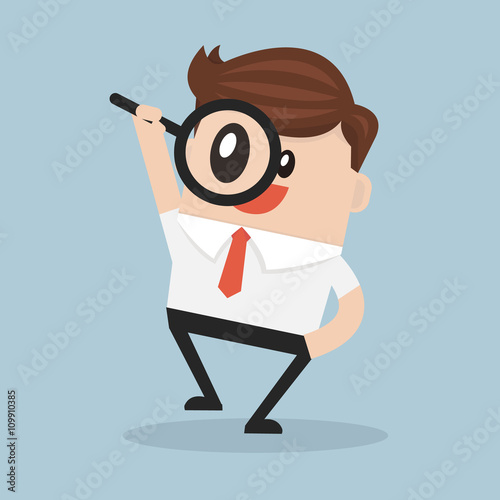 Businessman looking through a magnifying glass
