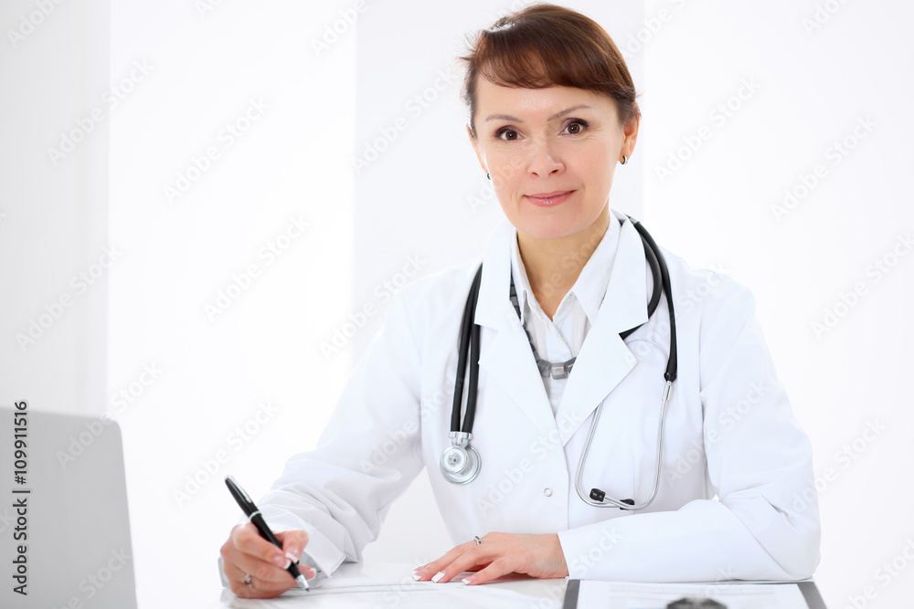Woman doctor filling up medical history at the desk Woman doctor filling up medical history at the desk