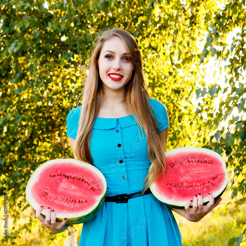 Beautiful blonde girl holding two halves of a sliced watermelon photo