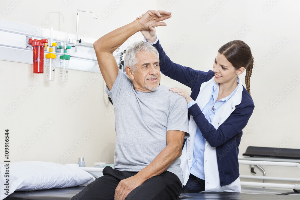 Obraz premium Physiotherapist Assisting Senior Man To Exercise