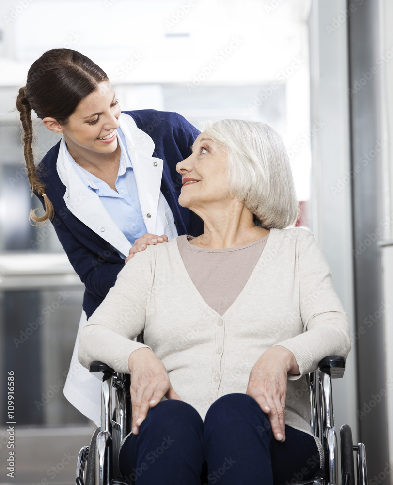 Obraz premium Physiotherapist Looking At Senior Patient Sitting In Wheelchair