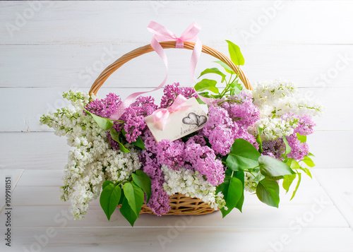Lilac bouquet in basket with paper greeting card with hearts and