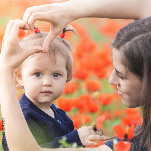 Mother with funny child outdoor at poppy flowers field photo