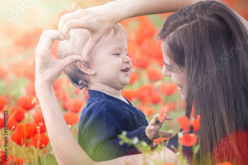 Mother with funny child outdoor at poppy flowers field photo