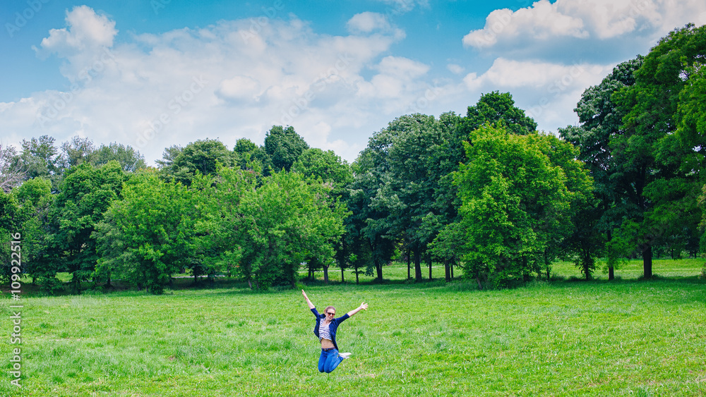 Happy woman Enjoying the nature. Young beautiful girl jumping on fresh air in green field. Provence smiling lady having fun outdoors