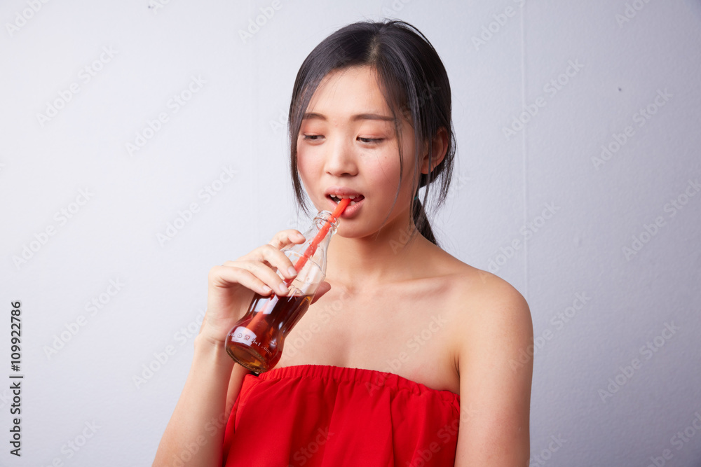 Chinese woman drinking carbonated drink through a straw Chinese woman drinking carbonated drink through a straw