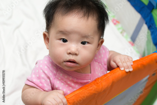 Asian baby in playpen