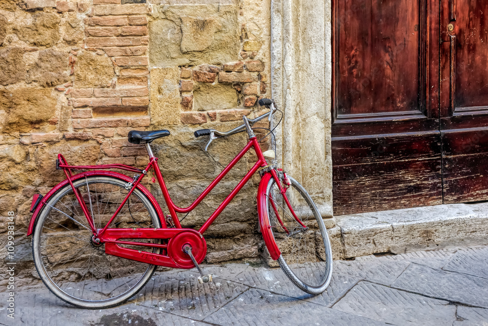 Red bicycle leaning against a wall in Pienza