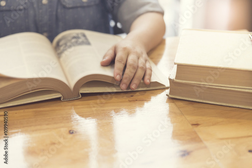 woman's hand reading book on wooden table