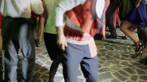 Legs of drunk people performing circle dancing all together at night party