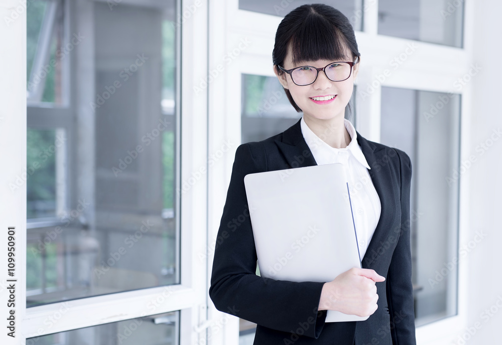 Modern business woman in the office, holding laptop Modern business woman in the office, holding laptop