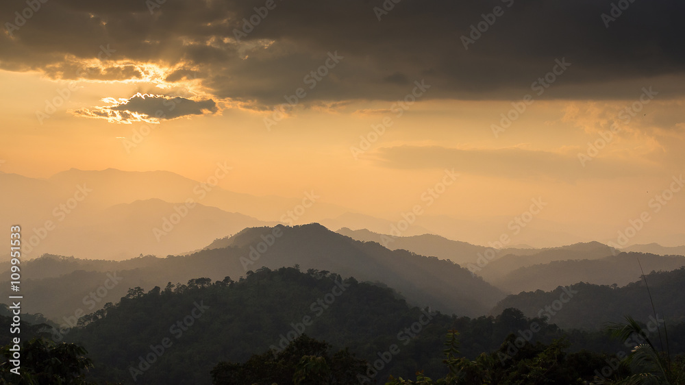 Fototapeta premium Sunset at the mountain landscape, the sun behind clouds