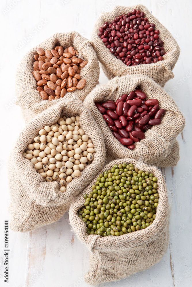 Obraz premium Assortment of beans and lentils in hemp sack on wooden backgroun
