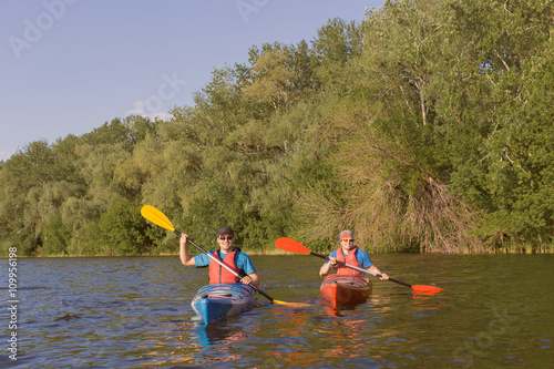 Men travel by canoe on the river in the summer a sunny day.