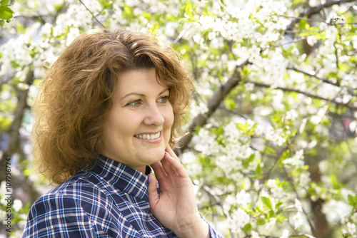 Portrait of woman with curly hair in cherry garden in spring