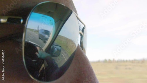 Close up shot of mans sunglasses showing the reflection of the road 