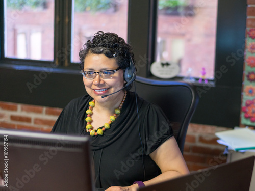 Middle Aged Hispanic Female In Office Environment Wearing Headph