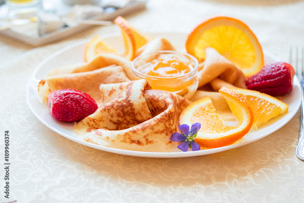 Closeup plate with pancakes with pieces of oranges, strawberries, jam and lavender flower Closeup plate with pancakes with pieces of oranges, strawberries, jam and lavender flower