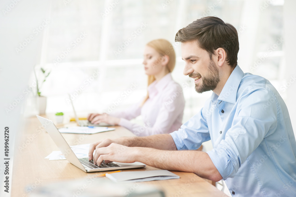 Cheerful male student is working on computer